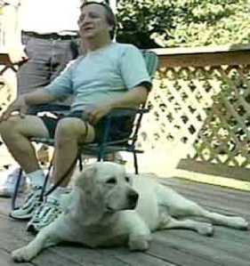 Blind owner seated with dog Dorado at foot